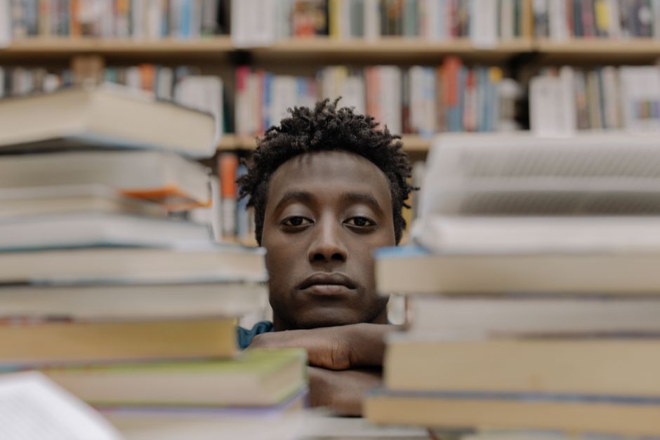 Jeune homme avec une pile de livres.